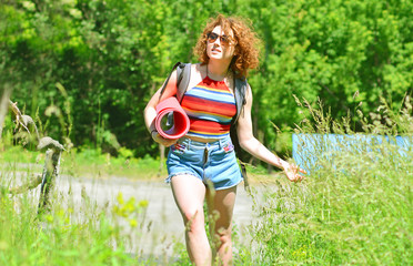 Beautiful cheerful girl looks around and goes on hike in summer day