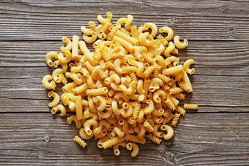 Yellow italian pasta in the heap on a wood background