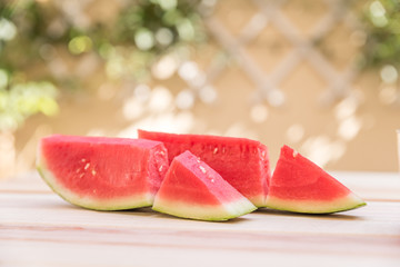 slices of watermelon on wooden table, mediterranean garden background