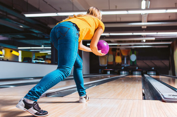 Woman throwing ball in bowling club. View from behind - obrazy, fototapety, plakaty