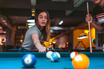 Young woman playing pool with friends