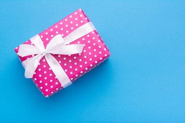 Hands holding wrapped gift box with colored ribbon as a present for Christmas, new year, mother's...