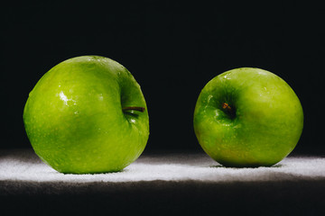 two fresh green apples on a dark background.