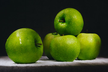 six fresh green apples on a dark background.