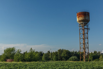 Water tower, sunlight and against a cloudy sky at dusk.