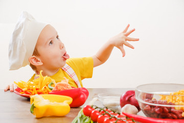 Healthy eating. Happy child prepares and eats vegetables in kitchen