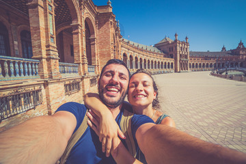 Naklejka premium szczęśliwa uśmiechnięta para robi selfie na placu Hiszpanii (Plaza de Espana) w Sewilli w Hiszpanii