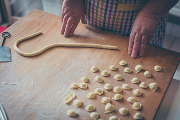 Process of production of pasta. woman hands make fresh pasta on wood board kitchen table