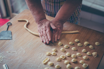 Process of production of pasta. woman hands make fresh pasta on wood board kitchen table