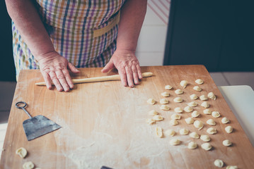 Process of production of pasta. woman hands make fresh pasta on wood board kitchen table