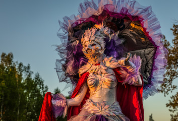 Fototapeta premium Fairy tale woman on stilts in bright fantasy stylization. Fine art outdoor photo.