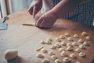 woman make homemade pasta gnocchi on wood board. Typical senior woman from south of Italy makes pasta from dough 