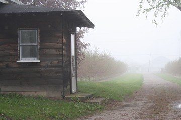 Fototapeta na wymiar Wooden building in front of misty road in spring
