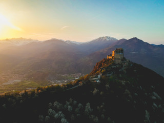 The Sacra di San Michele (Saint Michael's) Abbey, Turin, Italy, sunset shot aerial with mountains of Susa valley in background