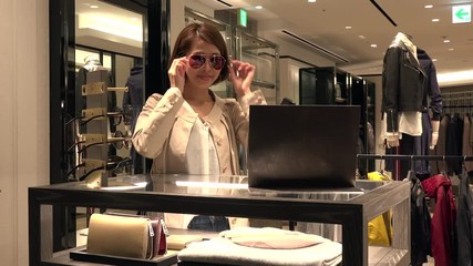 Asian people shopping for fashion goods and accessories. Japanese woman in luxury shop inside mall. Lady buying new sunglasses in store and talking to friendly sales assistant for help and assistance