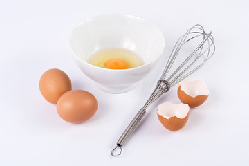 Egg white with the yolk in little bowl and other entries eggs with a whisking on white background. Food and cooking concept