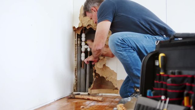 Domestic Plumber With Tools Repairing Leaking Pipe 
