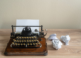 Old antique portable typewriter with screwed up paper on desk