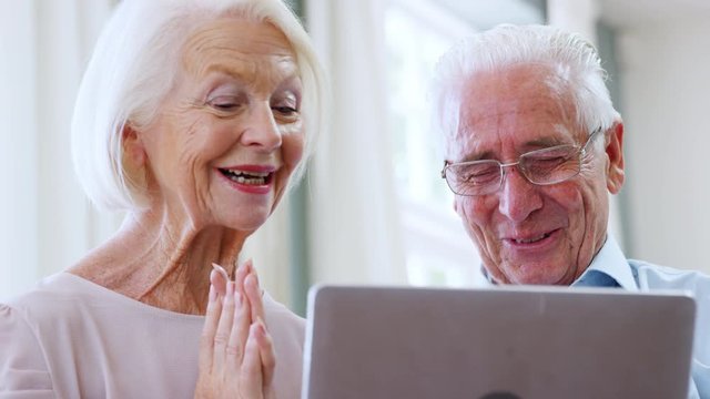 Senior Couple Using Laptop To Connect With Family For Video Call