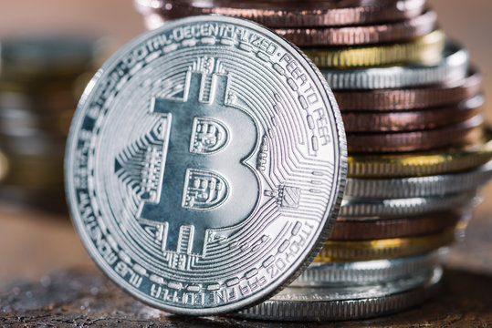 selective focus of silver bitcoin and pile of bitcoins behind