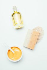 flat lay with orange clay mask in container, spoon, sponge, soap and perfume bottle isolated on white surface