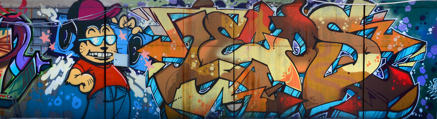 Straßenkunst. Abstraktes Hintergrundbild eines vollständig fertiggestellten Graffiti-Gemäldes in Beige- und Orangetönen mit Zeichentrickfigur © mehaniq41