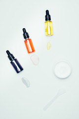 flat lay with cosmetic bottles with pipes, smudges, spoon and clay mask in container isolated on white surface