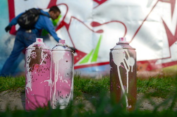 A few used paint cans against the background of the space with the wall on which the young guy...
