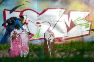 A few used paint cans against the background of the space with the wall on which the young guy...