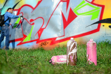 A few used paint cans against the background of the space with the wall on which the young guy...