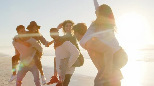 Group Of Friends Having Piggyback Race On Winter Beach Together