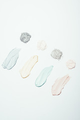 top view of various clay powder and colorful clay mask smudges placed in row isolated on white surface