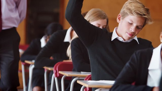 Teenage Student Sitting Examination Asking Teacher Question