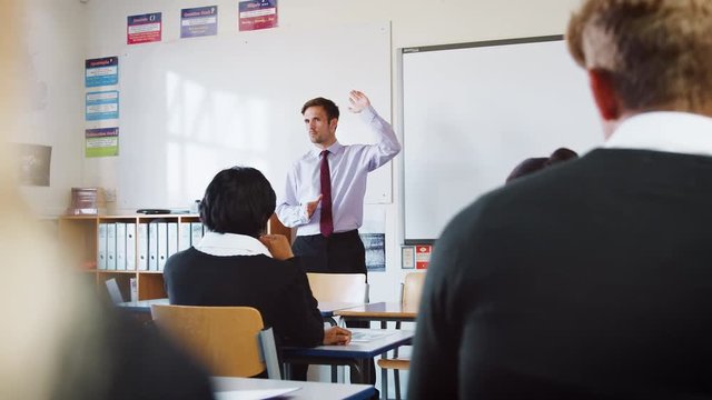 Teenage Students Listening To Male Teacher In Classroom