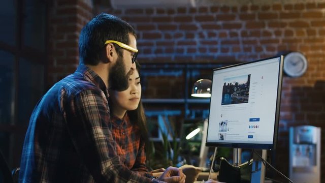 Side view of bearded man in glasses and beautiful asian woman surfing Internet and looking through web sites with concentration
