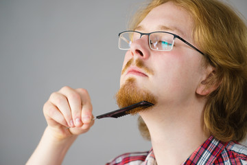 Man brushing his beard using comb