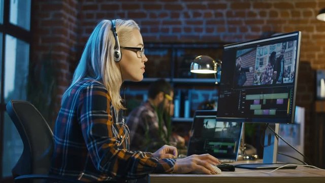 Side view of casual woman in headphones working on computer and editing video with color correction