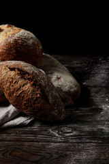 close up shot of various types of bread and sackcloth on wooden table covering by flour