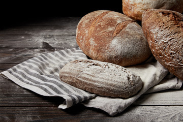 closeup image of various types of bread, flour and sackcloth on wooden table
