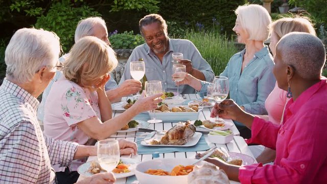 Group Of Senior Friends Enjoying Outdoor Dinner Party At Home