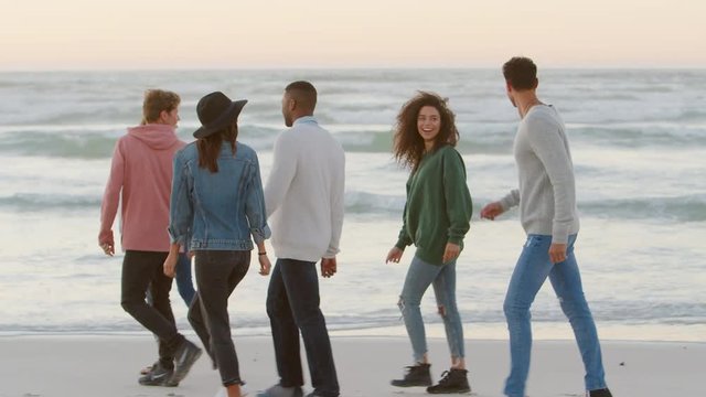 Group Of Friends Walking Along Winter Beach Together