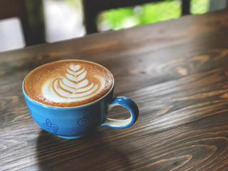Morning Coffee cup,latte art coffee cup on the wooden  background with vintage cafe light. Copy space and vintage style