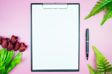 Women's stylish table. Workspace with blank white paper free space and pen in desk with flowers on pink pastel background for magazines, websites, media, Instagram. Flat lay, top view.