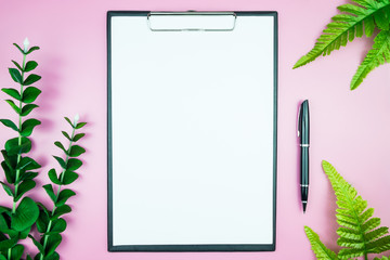 Women's stylish table. Workspace with blank white paper free space and pen in desk with flowers on pink pastel background for magazines, websites, media, Instagram. Flat lay, top view.