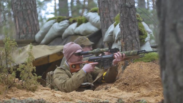Soldiers in camouflage with combat weapons are being fired in the shelter of the forest, the military concept