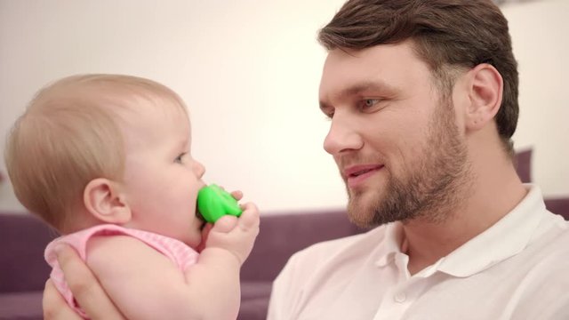 Bearded daddy kissing baby infant. Close up of father holding child with toy. Father kissing baby. Parent care kid. Family tenderness. Sweet parenting. Happy man with baby
