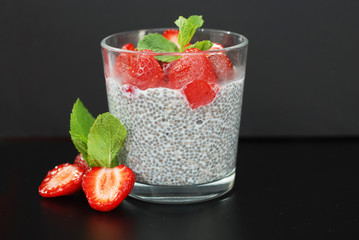 Healthy Dessert Pudding Chia Seeds in Yogurt, Yogurt and Strawberries and Mint in the Glass Bowls. Black Background.