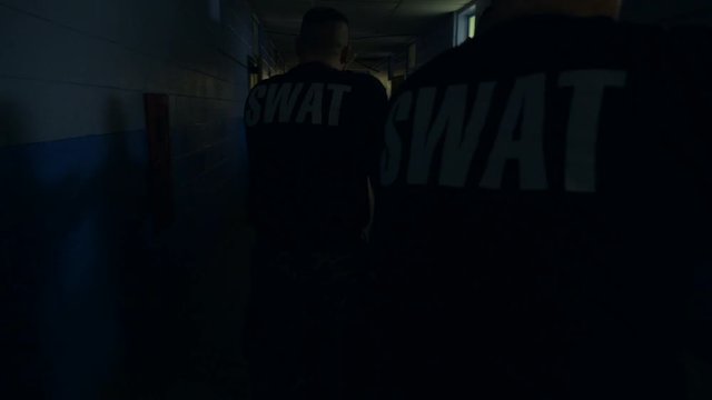 A squad of SWAT team police walk in a school with guns drawn to train for responding to school shootings.