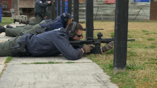 Police officer shoots an assault rifle during target practice at a gun range.