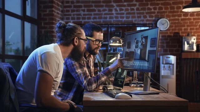 Side view of diverse group of men sitting at table with computer and coworking on creation of new cartoon movie